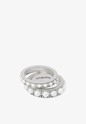 Deux bagues en argent ornées de perles blanches incrustées autour des anneaux, une plus petite à l'intérieur de la plus grande, "ALLSAINTS" gravé à l'intérieur de la bague plus petite.