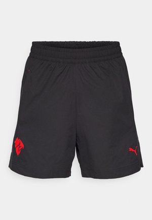 Shorts de sport noirs avec une taille élastique, arborant un logo de lion rouge et un logo Puma rouge sur le côté inférieur. Tissu léger, texture lisse.