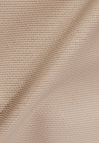 Tissu beige texturé avec un motif fin tissé, affichant un léger éclat et de légères ondulations à la surface.