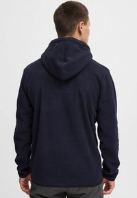 Marineblauwe fleece hoodie met een zachte textuur, voorzien van een capuchon, lange mouwen en een rechte snit. Minimale hardware en geen zichtbare patronen.
