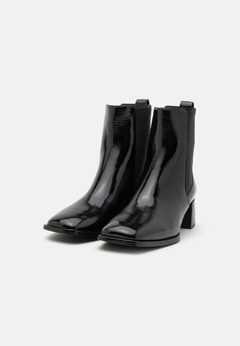 Schwarze Lackleder-Ankle Boots mit spitzer Zehenpartie, elastischen Seitenpanele und Blockabsatz. Glatte Textur, minimalistisches Design.