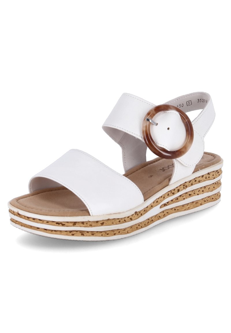 Sandales blanches à talon compensé en liège, avec un grand accent rond marron sur la bride, texture lisse et design ouvert.