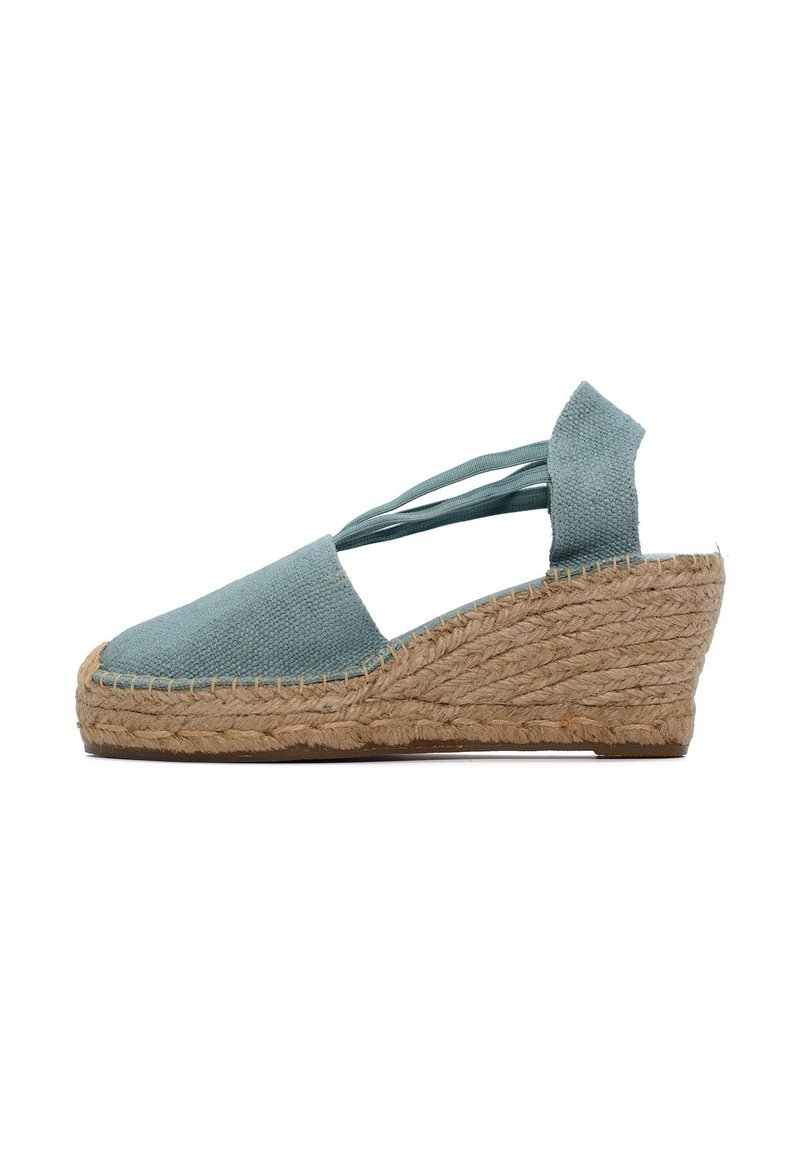 Espadryle na koturnie z jasnoniebieskiej płótna, obcas owinięty jutą i krzyżujące się paski na kostkach. Teksturowana powierzchnia i zaokrąglony kształt.