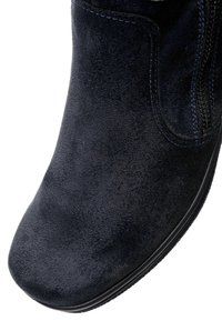 Sort ankelstøvle af ruskind med rundet tå og synlig sidelukning, der viser detaljeret tekstur og syning.