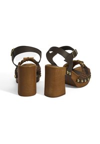 Braune High-Heels Sandalen mit einem klobigen Absatz, featuring ein geflochtenes Design und dekorative goldene Nieten. Doppelte Riemenkonstruktion mit verstellbarem Schnallenverschluss.