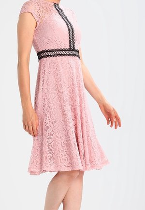 Abito in pizzo rosa con corsetto aderente e gonnellina svasata. Dettagli in pizzo nero lungo il collo e in vita. Maniche corte.