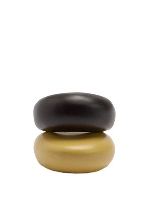 Dwa gładkie, zaokrąglone kamienie ułożone pionowo, górny ciemnoszary, dolny jasnobrązowy, na białym tle.