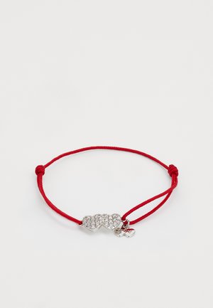 Bracelet en cordon rouge avec un charme en forme de cœur en argent orné de plusieurs strass transparents et d'un petit pendentif en forme de cœur.