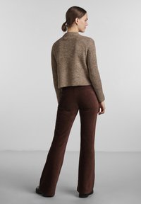 Brown, textured knitted sweater with a cropped cut and long sleeves, paired with wide-leg, dark brown corduroy pants.