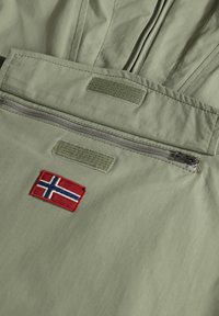 Tkanina w kolorze oliwkowym z kieszenią na zamek błyskawiczny, ozdobiona naszywką z haftowanym norweskim flagą w kolorach czerwonym i niebieskim oraz dwoma paskami na rzep.