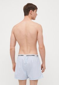 Boxers rayés bleu clair en tissu doux, dotés d'une ceinture noire avec le logo "JACK & JONES". Coutures visibles et coupe décontractée.