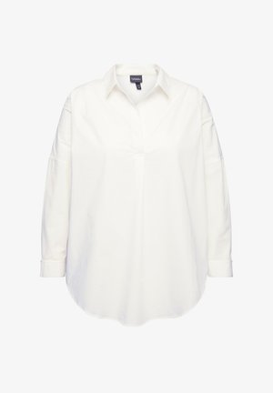 Biała bawełniana koszula zapinana na guziki z kołnierzykiem, długimi rękawami i zaokrąglonym dołem. Posiada gładką fakturę i minimalistyczny design.