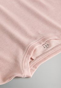 Lichtroze katoenen t-shirt met een gladde textuur, voorzien van een ronde halslijn en een zichtbaar label op de binnennaad. Eenvoudig ontwerp, zonder patronen.