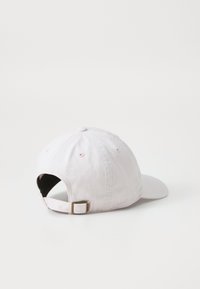 Lys rosa bomulds baseball cap med en buet skygge, justerbar rem og en knap på toppen, med ventilationshuller langs siderne.