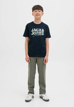 Marineblauwe t-shirt met multi-kleurige "JACK & JONES" grafiek, olijfgroene broek en witte sneakers met zwart en grijs accent.