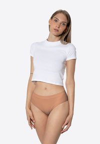 T-shirt blanc court à manches courtes associé à un sous-vêtement taille haute de couleur marron clair. Tissu lisse avec un design sans couture.