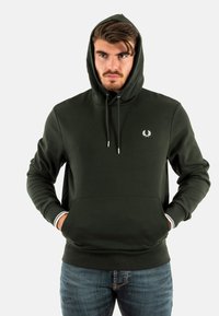 Sudadera con capucha de tela verde oscuro, con un bolsillo frontal, puños acanalados con acentos blancos y un logo en la parte izquierda del pecho.