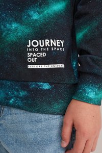 Felpa nera con un motivo galattico in verde, blu e bianco, con testo stampato: "VIAGGIO NELLO SPAZIO SPAZIO DISTANZIATO ESPLORA L'UNIVERSO."