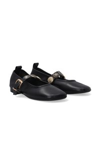 Schwarze Lederschuhe mit runder Zehenform, flachem Absatz und einer dekorativen Schnalle mit geprägten Metallakzenten. Glatte Textur; minimales Design.