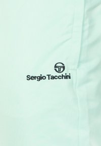 Licht mintgroene stof met een subtiel textuurpatroon. Bevat zwarte borduursels van het logo en embleem van "Sergio Tacchini".