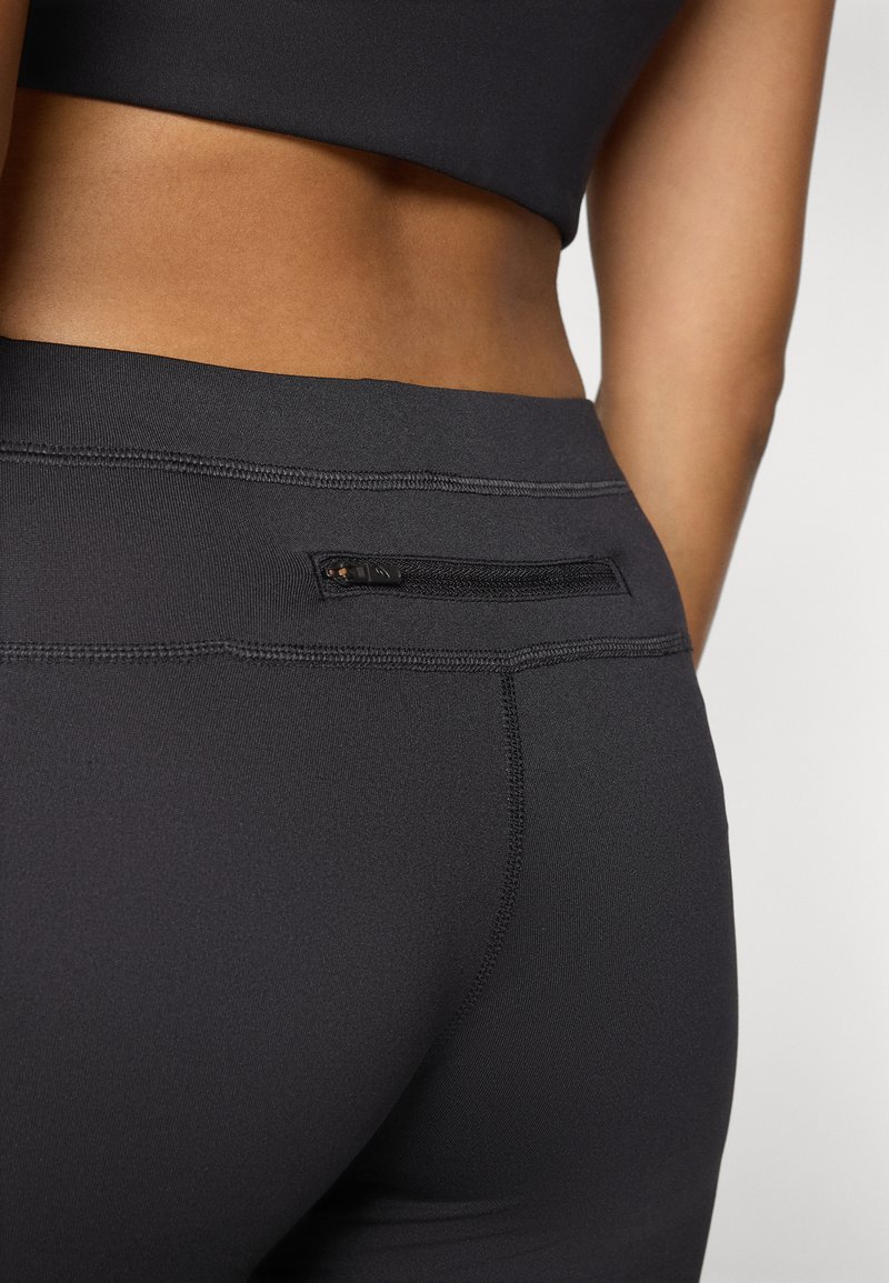 Schwarze Sportleggings mit glatter Textur, ausgestattet mit einer kleinen Reißverschlusstasche auf der Rückseite und kontrastierendem Nähen entlang des Bundes.