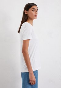White short-sleeved T-shirt in lightweight fabric with a relaxed fit. Features a classic crew neckline and smooth texture.