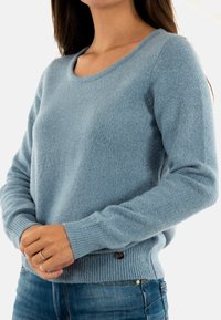 Maglione lavorato a maglia azzurro chiaro con scollo rotondo, polsini e orlo a costine, realizzato in filato testurizzato con un leggero luccichio, arricchito da un logo.