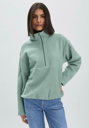 Pull en polaire vert menthe avec un col haut, fermeture éclair à mi-hauteur et coupe décontractée. Texture douce ; il est doté de manches longues et d'une poche à l'avant.