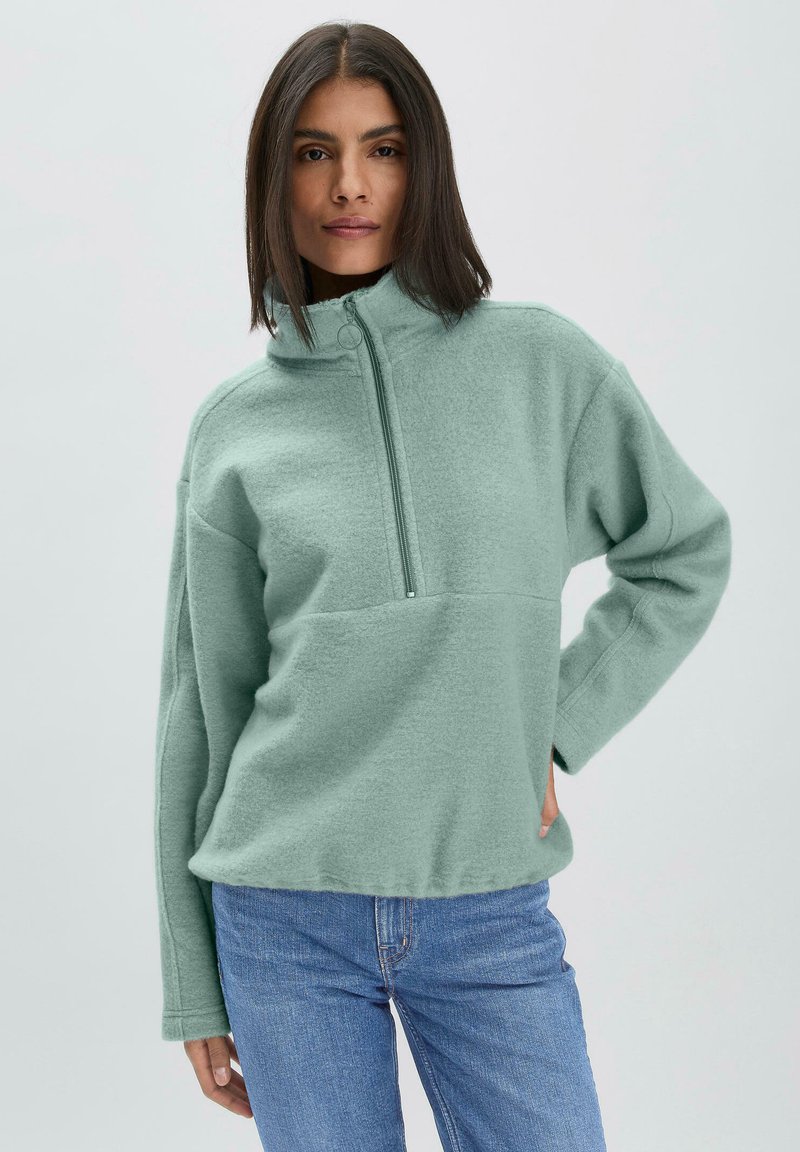 Pull en polaire vert menthe avec un col haut, fermeture éclair à mi-hauteur et coupe décontractée. Texture douce ; il est doté de manches longues et d'une poche à l'avant.