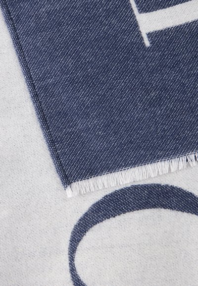 Gros plan de deux morceaux de tissu tissé qui se chevauchent, l’un bleu foncé avec un bord effiloché et l’autre clair avec un cercle partiel bleu foncé.