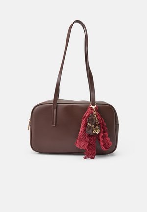 Sac à épaule rectangulaire marron avec de longues anses, orné d'une écharpe en dentelle rouge et d'un petit charme marron avec un détail cœur doré.