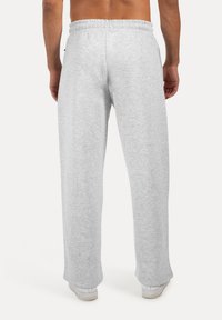 Pantalones de chándal grises hechos de una tela suave, con un ajuste relajado, cintura elástica y puños cerrados. Sin marcas ni patrones visibles.