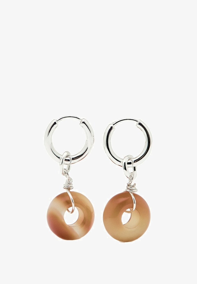 Zilveren hoop oorbellen hebben een transparante, lichtbruine ronde hanger met een centrale opening. De hanger heeft een gladde textuur en subtiele kleurnuances.