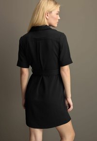 Must must dress lühikeste varrukatega, krae ja vöödiga taljes. Omab sujuvat tekstuuri ja lihtsat disaini. Tagakaanet on näidatud.