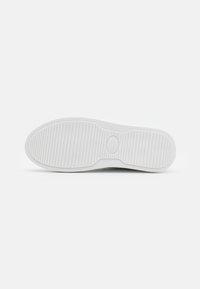 Witte rubberen schoenzool met een gladde oppervlakte, horizontale ribbels voor grip, en een rond logo in het midden.