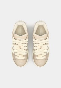 Scarpe da atletica di un beige chiaro con una tomaia in suede e sintetico, spesse stringhe color crema e tre strisce bianche orizzontali sui lati.
