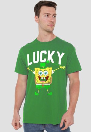 Green cotton t-shirt featuring a large graphic of a cartoon character with a happy expression, arms outstretched, and the word "LUCKY" in white.