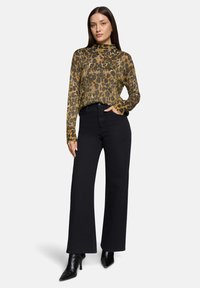 Dopasowana bluzka z długim rękawem w panterkę w odcieniach złota i czerni; zestawiona z czarnymi, szerokimi spodniami z wysokim stanem oraz czarnymi, spiczastymi botkami za kostkę.