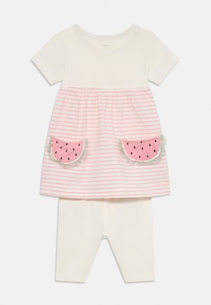 Maglietta bianca a maniche corte con strisce rosa, caratterizzata da applicazioni a forma di anguria sulla tasca; abbinata a leggings bianchi uni. Tessuto in cotone morbido.