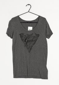 Grå kortærmet t-shirt lavet af blødt stof, med et sort blonde trekantmønster og ordet "Guess" i skrifttype i midten.