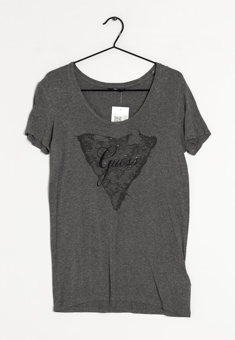 Grå kortærmet t-shirt lavet af blødt stof, med et sort blonde trekantmønster og ordet "Guess" i skrifttype i midten.