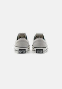 Grå mocka låg-top sneakers med svarta och vita gummisulor. Har en turkos insida och "Converse All-Star"-logga på hälen.