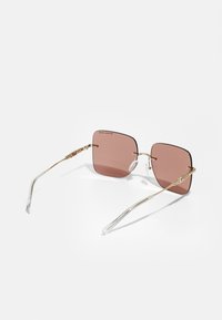 Óculos de sol quadrados com lentes cor-de-rosa e uma fina armação em metal dourado. Acentos de plástico transparente nas hastes com detalhes intrincados.