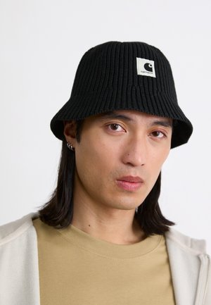 Sombrero de cubo de punto negro con textura acanalada y un parche de logo cuadrado. La visera es ancha, ofreciendo un diseño casual y funcional.