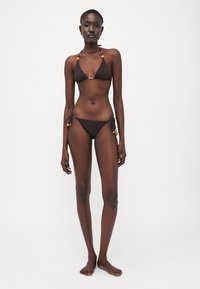 Bruin triangulaire bikini-set met decoratieve hardware en verstelbare banden, vervaardigd van een gladde stof met een elegante uitstraling.