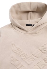 Felpa beige con un design grafico testurizzato. Presenta un cappuccio con cordoncino e un tessuto morbido. Etichetta del marchio visibile vicino al collo.