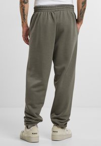 Gray sweatpants in soft cotton blend with an elastic waistband; relaxed fit; side pockets; matched with beige sneakers featuring branding.