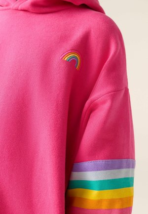 Sudadera de un brillante color rosa con un pequeño arco iris bordado en el pecho y bandas de rayas de arco iris en una manga.
