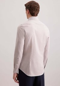 Camicia da uomo a maniche lunghe in un tessuto leggero con un motivo a quadri marrone e crema. Presenta un colletto appuntito e polsini abbottonati.