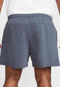 Graue Sportshorts mit weichem Material, einem elastischen Bund und einer lockeren Passform. Kurz geschnitten mit geradem Saum, geeignet für Sportbekleidung.